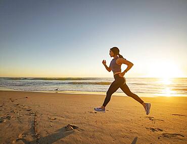 Woman jogging on beach at sunset