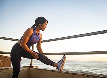 Woman stretching on beach at sunset