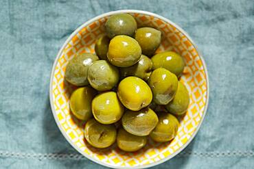 Overhead view of green olives in bowl