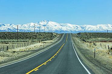 USA, Nevada, Winnemucca, Highway 95 crossing desert landscape with snowcapped mountains in distance