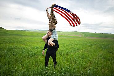 Young couple with American flag in wheat field