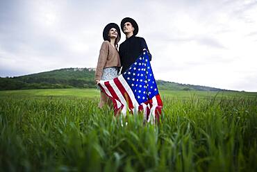 Young couple holding American flag in wheat field