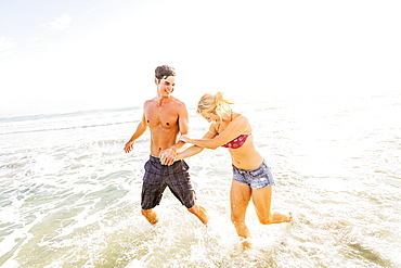 Young couple running in surf holding hands, Jupiter, Florida