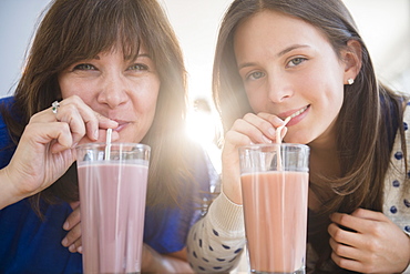 Portrait of mother and daughter (14-15) drinking milkshakes