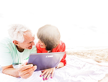 Couple with digital tablet lying on blanket at beach, Jupiter, Florida