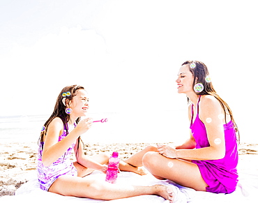 Mom and her daughter (6-7) sitting on blanket on beach, Jupiter, Florida