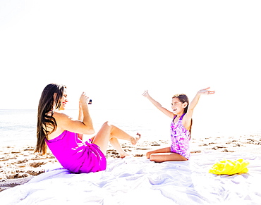 Mom taking picture of her daughter (6-7) on beach, Jupiter, Florida