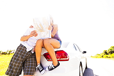 Couple at back of car looking at map, Tequesta, Florida