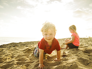 Girl (4-5) and boy (2-3) playing on beach, San Clemente, California