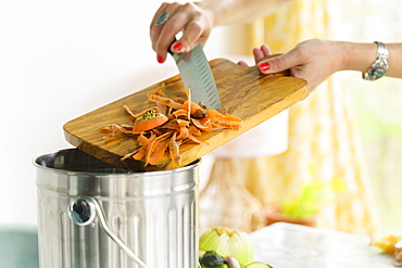 Woman putting carrot peels into compost bin