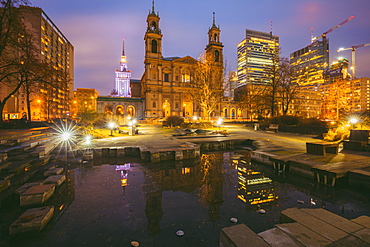Poland, Masovia, Warsaw, Church and illuminated city skyscrapers reflecting in pond at night