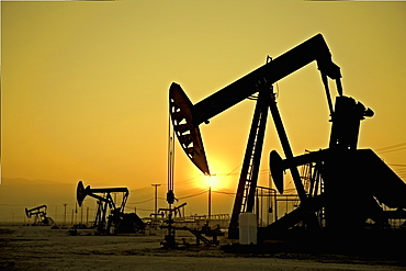 Silhouette of pump jacks in oil field at sunset