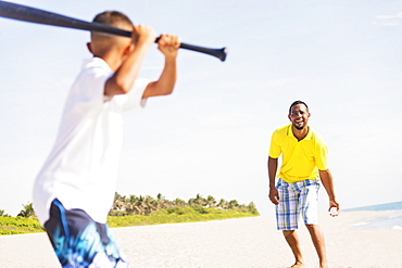 Father and son (10-11) playing baseball on beach, Jupiter, Florida