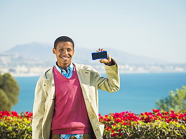 Portrait of smiling man holding smartphone, Dana Point, California