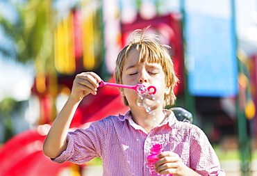 Boy (8-9) blowing bubbles, Jupiter, Florida, USA