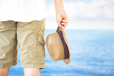 Studio Shot Rear view of man holding straw hat