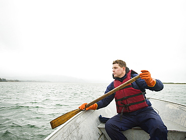 Portrait of young man paddling boat, Rockaway Beach, Oregon