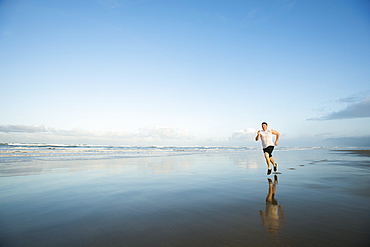 Young adult man running on beach, Rockaway Beach, Oregon