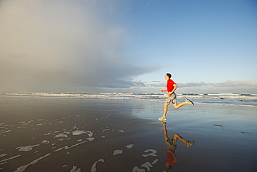 Young adult man running on beach, Rockaway Beach, Oregon