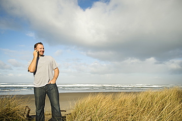 Man on phone while standing on beach, Rockaway Beach, Oregon