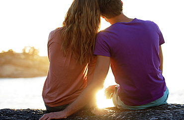 Rear view of young couple sitting at beach