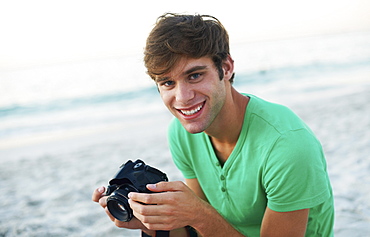 Portrait of young man taking pictures at beach