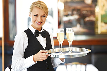 Portrait of waitress holding champagne flutes on tray