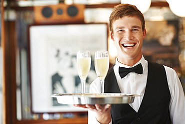 Portrait of waiter holding champagne flutes on tray