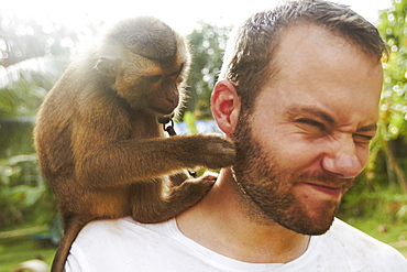 Portrait of adult man with macaque monkey sitting on his shoulder, Thailand 