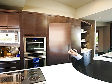 Young woman bustling around in modern domestic kitchen