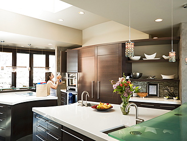 Young woman bustling around in modern domestic kitchen