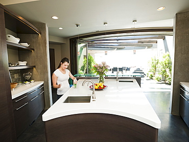 Young woman bustling around in modern domestic kitchen