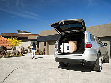 Young woman unpacking shopping from car parked in yard, USA, Utah, St. George