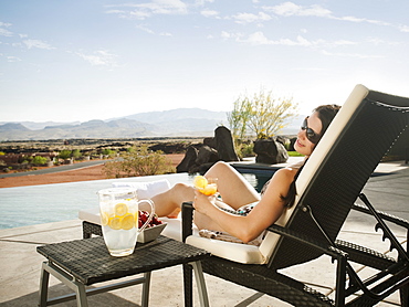 Young attractive woman enjoying cocktail by swimming pool, USA, Utah, St. George