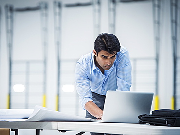 Indian architect using laptop in empty warehouse