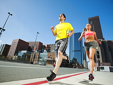 USA, California, Los Angeles, Young man and young woman running on city street, USA, California, Los Angeles