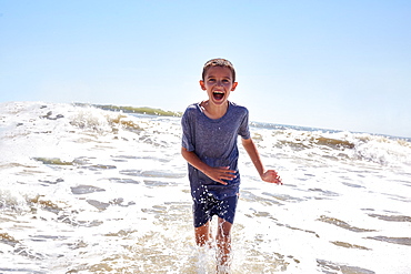 Portrait of smiling boy (8-9) playing in sea waves