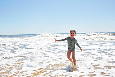 Portrait of smiling girl (2-3) playing in sea waves