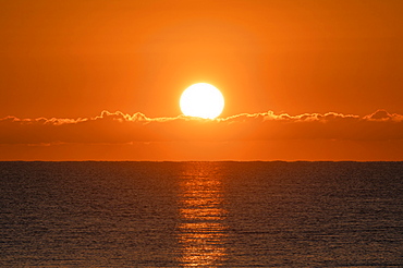 Blazing sunrise in orange sky over ocean