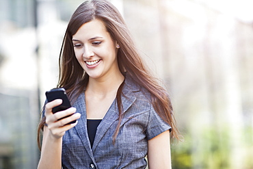 Young elegant woman standing and using mobile phone