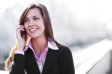 Smiling young businesswoman talking via mobile