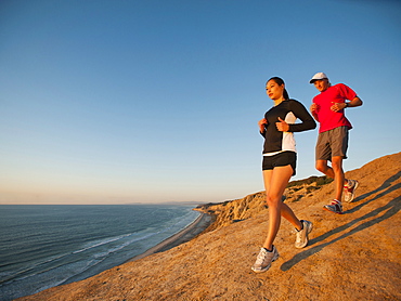 USA, California, San Diego, Man and woman jogging along sea coast