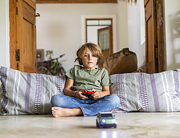 Boy (8-9) playing with remote-control toy car at home