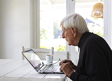 Senior man working on laptop computer at home