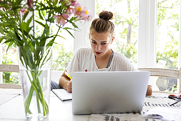 Girl (16-17) using laptop at home