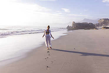 South Africa, Hermanus, Girl (16-17) walking on Sopiesklip beach in Walker Bay Nature Reserve