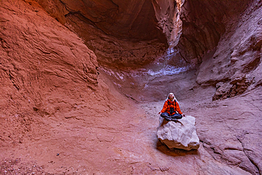 United States, Utah, Escalante, Senior female hiker sitting on rock in canyon