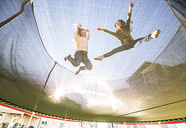 Low angle view of sisters (10-11, 12-13) jumping on trampoline