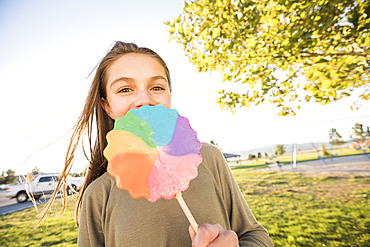 Portrait of girl (12-13) with colorful lollipop in park