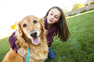 Girl (12-13) with Golden Retriever on lawn